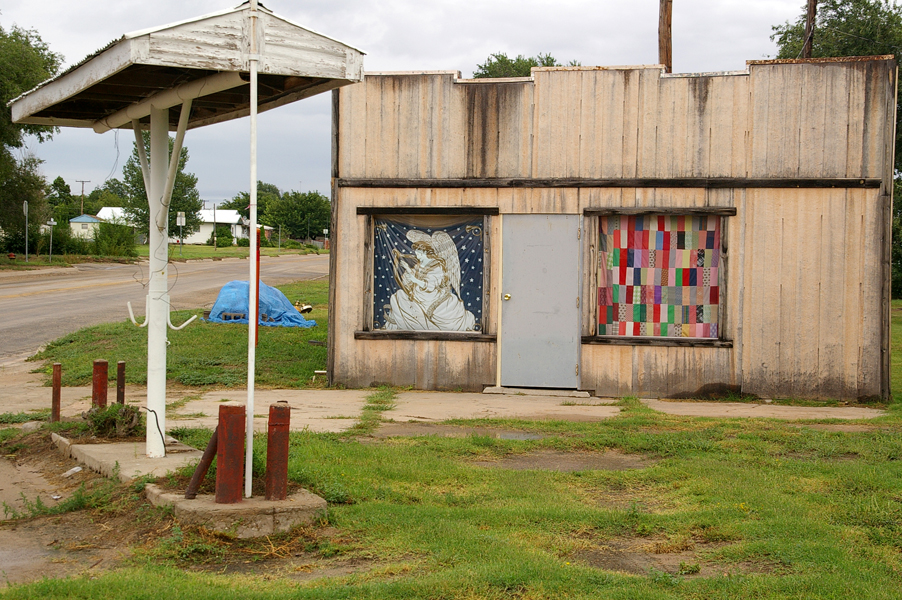 Lefors, TX : HOMEMADE QUILTS grace the windows of an abandoned gas station.