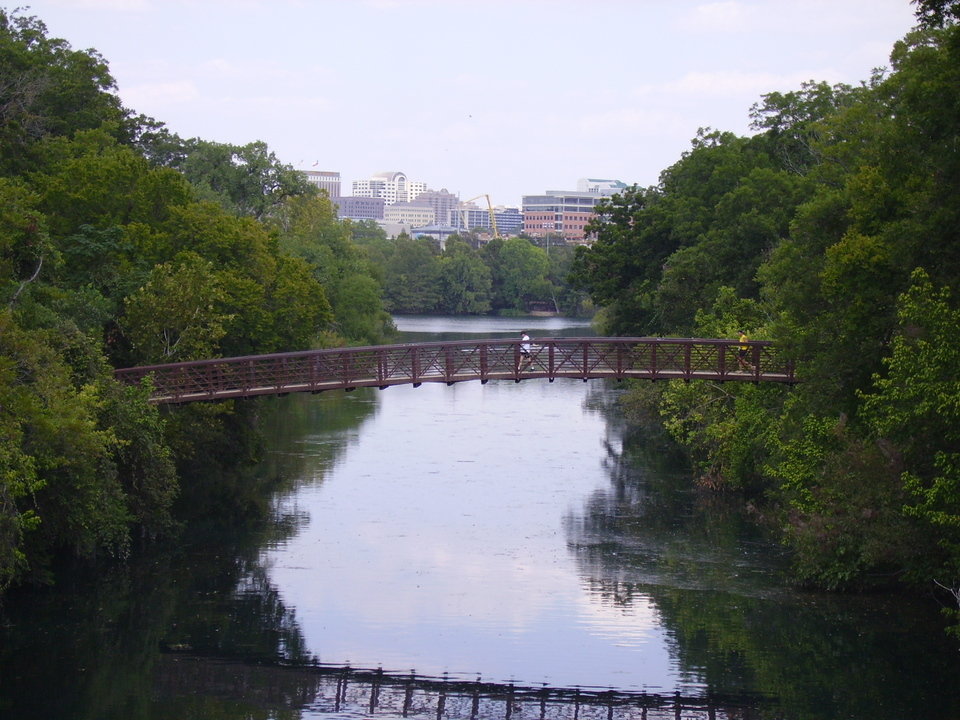 Austin, TX: Walking bridge over Barton Springs with view of the city.