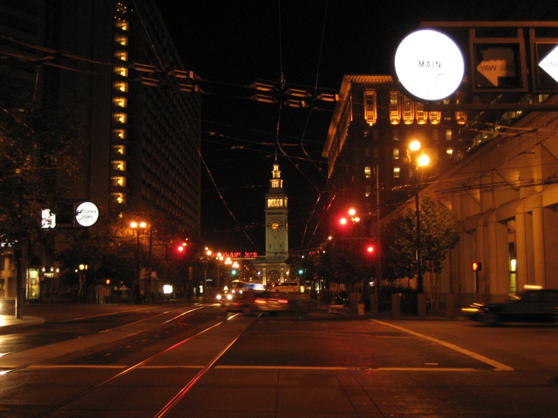 San Francisco, CA: Market & Main at night, the SF Ferry Building looms bright