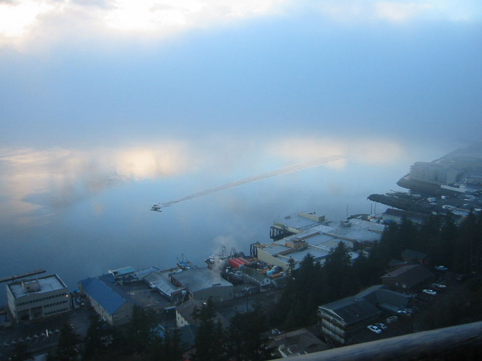 Ketchikan, AK: A floatplane taxis out of a fogbank over a mirror-like Tongass Narrows