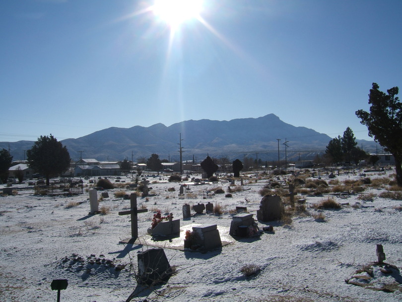 Truth or Consequences, NM: City cemetery with sun rising over Turtleback Mountain in background