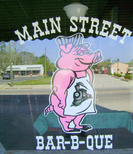 Branchville, SC: Branchville, SC's, Main Street Bar-B-Que Restaurant store-front window logo, with reflections of business and parking lot across Main Street.