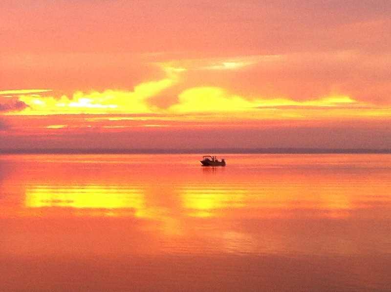 Montverde, FL: Morning sunrise on Lake Apopka with a fishing boat out on the lake.